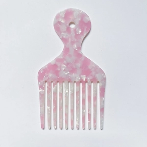 Macro view of pink marble acetate hair pick showing fine teeth texture and hanging hole