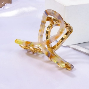 Large vintage gold metal hair claw with marble resin inserts on a silk background