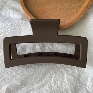 Macro detail of large 13cm matte brown rectangular hair claw clip on wooden display