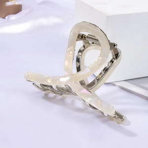 Detail of acetate shark hair claw with pearlescent marble texture and silver metal spring