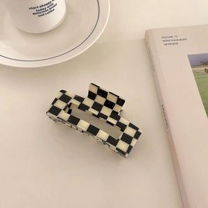 Detail of a rectangular acetate hair claw clip featuring a black and white checkerboard pattern