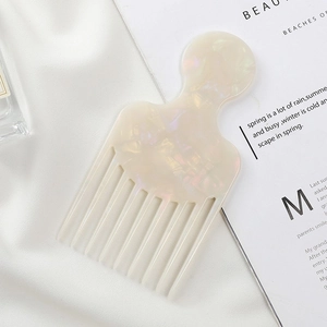 Detailed macro view of pearlescent acetate hair comb on silk fabric with marble pattern