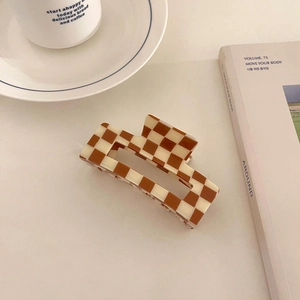 Brown and beige checkered acetate hair claw clip styled with coffee and lifestyle magazine