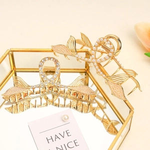 Detailed macro of golden fishtail hair claws with elegant pearls and sparkling rhinestones