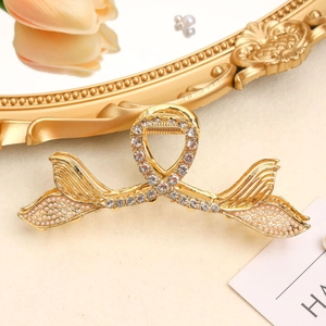 Close-up of golden mermaid tail hair claw clip with pearls and sparkling rhinestones