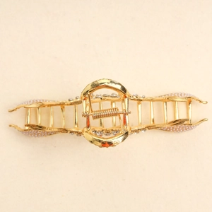 Detailed macro view of golden fishtail hair claw clip with white pearls and crystals