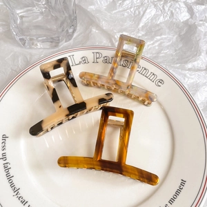 Three acetate rectangle hair claws in tortoise shell and marble patterns on white plate