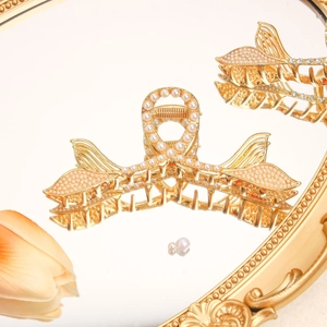 Detail of gold fishtail hair claw clip with white pearls on a vintage mirror