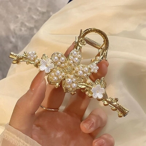 Eleganter goldener Blumen Haarklammer mit Kunstperlen und Strass auf beigem Stoff