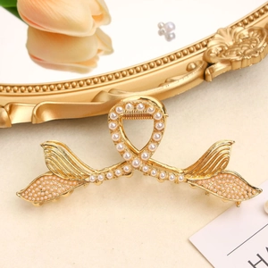 Elegant gold fishtail hair claw clip with white pearls on a vintage background
