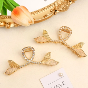 Detail of elegant gold fish tail hair claws with white pearls and sparkling rhinestones