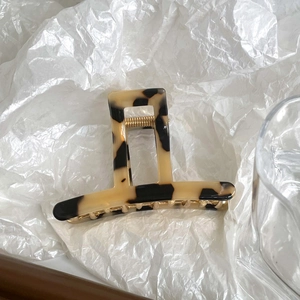 Detail of leopard print acetate hair claw clip with golden spring and hollow design