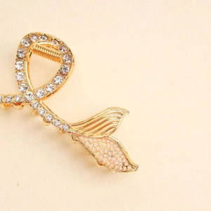 Detail of fishtail hair claw with gold metal finish and white pearls decoration