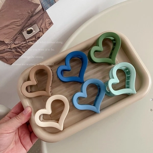 Set di sei mollette per capelli opache a forma di cuore in vari colori in un vassoio beige