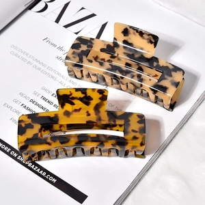 Detail of two tortoise shell hair claws in beige and amber acetate on a magazine background