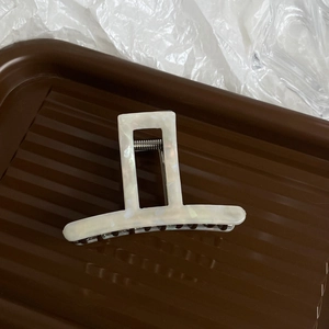 Macro detail of cream marble acetate hair claw clip with strong metal spring