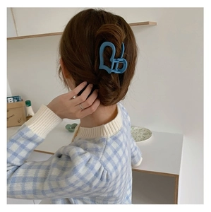 Pinza per capelli a cuore blu opaco mostrata su una modella con capelli castani mossi