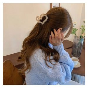 Dettaglio della molletta per capelli a cuore color crema su maglione lavorato a maglia