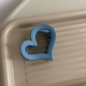Dettaglio della molletta per capelli a cuore blu opaco con design minimalista