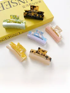 Detail showing various acetate claw clips in leopard print and marble patterns on a book