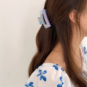 Detail view of large acetate hair claw clip with purple and blue marble pattern on hair