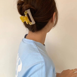 Detail view of large acetate hair claw clip with yellow and white marble texture on hair