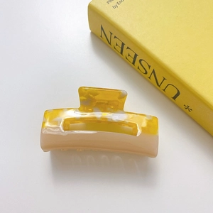 Close-up of yellow and beige marble pattern acetate square cutout hair claw clip
