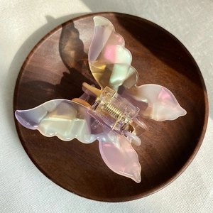 French vintage butterfly hair claw clip with pearlescent acetate finish on wooden tray