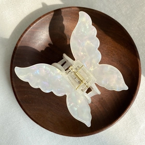 Detailed macro view of white acetate butterfly hair claw clip with marble texture