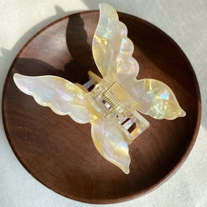 Macro shot of butterfly hair claw in pearlescent cream acetate on wooden tray