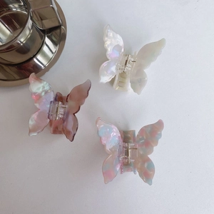 Detailed macro view of butterfly hair claws in pearl white and iridescent resin finishes