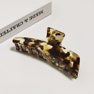 Macro detail of large tortoiseshell acetate hair claw clip on minimalist book background