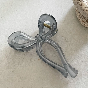 Detail of dark gray translucent acrylic bow hair claw with gold metal spring