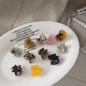 Mini pinces à cheveux en acétate en forme de chat aux couleurs marbrées sur plateau