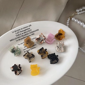 Mini pinces à cheveux chat en acétate coloré sur un plateau avec perles et tissu