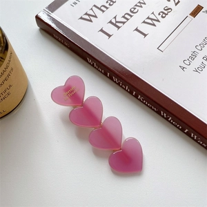 Détail d'une barrette à cheveux rose en forme de cœur en acétate sur bureau blanc