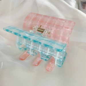 Détail d'une pince à cheveux à carreaux rose et bleu avec ressort en métal doré