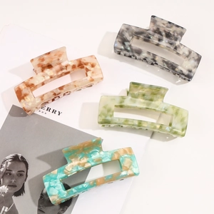 Detailed view of four acetate hair claws with elegant marble patterns and square hollow design