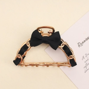Detail of metal chain hair claw clip with black silk ribbon bow and golden teeth
