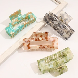 Detail view of four large cellulose acetate hair claws with marble and tortoiseshell patterns