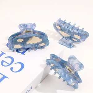 Detail of blue marble cellulose acetate hair claws with white cloud patterns and metal springs