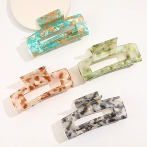 Detailed macro view of four large acetate hair claws featuring elegant marble patterns