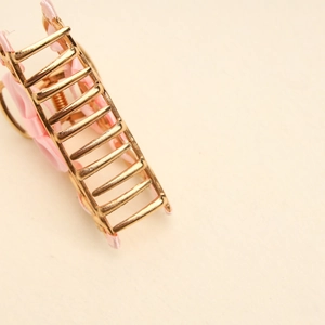 Detail of golden metal claw clip featuring a soft pink satin bow with secure spring grip