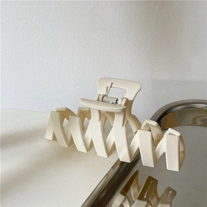 Minimalist cream-colored matte hair claw clip with large wavy teeth for elegant styling