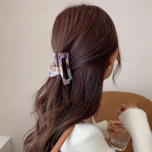 Marbled acetate hair claw clip with purple and blue hues on wavy brown hair