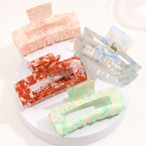 Set of four colorful acetate hair claws in marble texture on white round pedestals