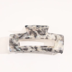 Detail of a rectangular acetate hair claw with grey marble pattern and hollow center