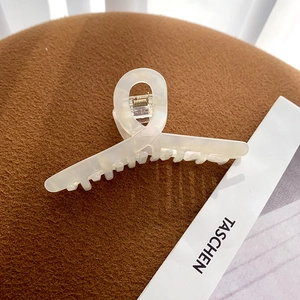 Macro detail of cream-colored acetate hair claw clip with elegant marble texture