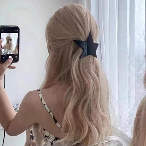 Black star hair clip worn on blonde wavy hair showing minimalist y2k hair accessory style