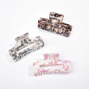 Three acetate hair claws with marble textures in tortoiseshell, white and pink patterns